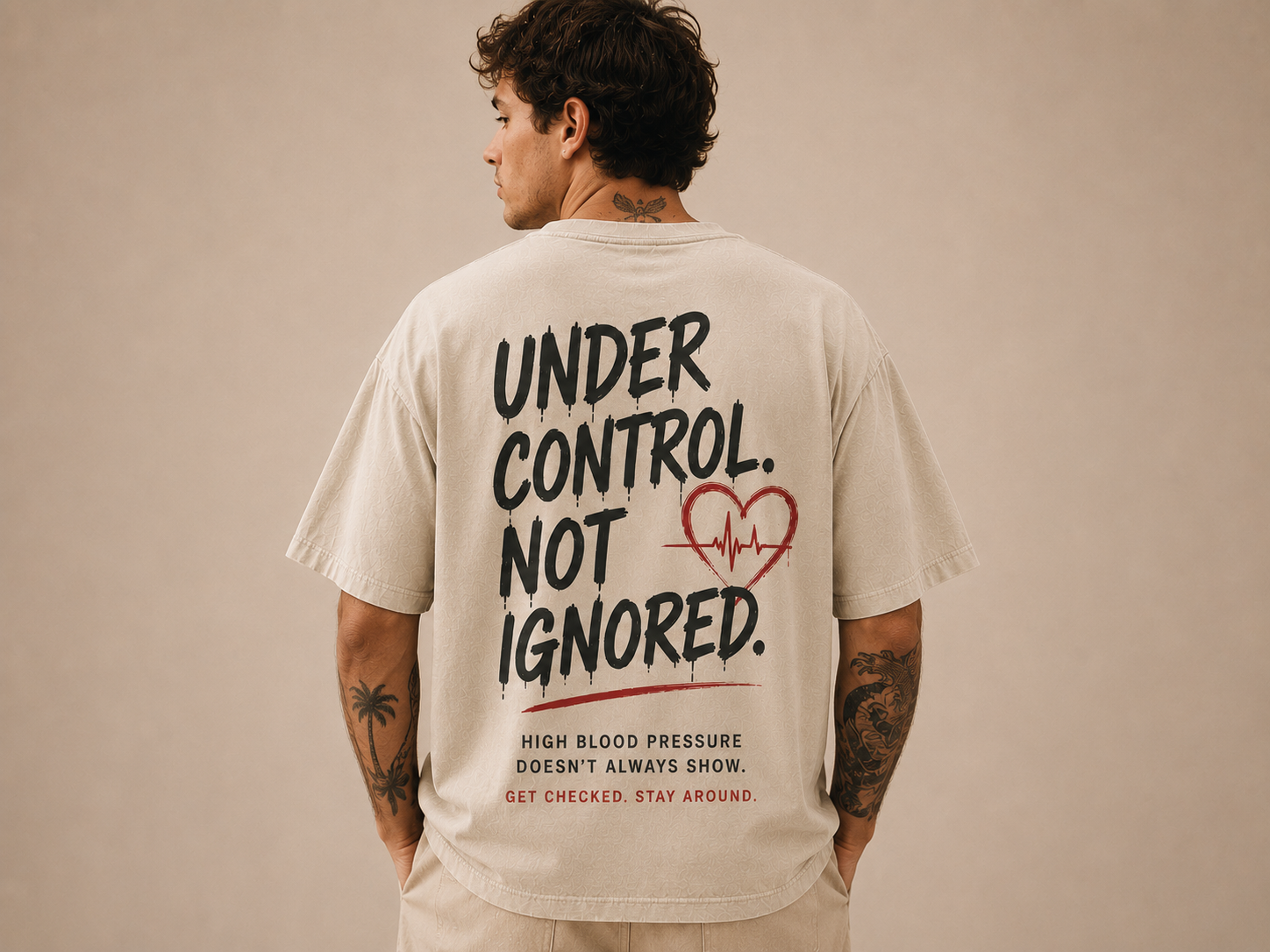 Rückenansicht eines sandfarbenen Oversize-Shirts mit dem Print „Under control. Not ignored.“ zum Thema Bluthochdruck
