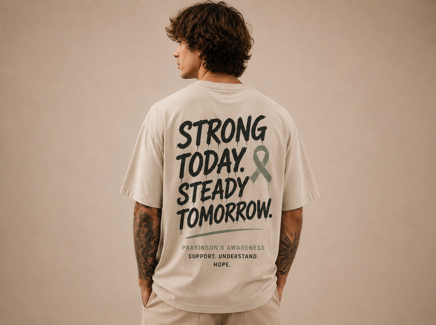 Rückenansicht eines sandfarbenen Oversize-Shirts mit dem Print „Strong today. Steady tomorrow.“ zum Thema Parkinson